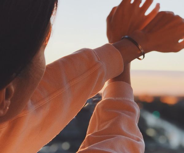 Man stretching his arms up facing the sunrise